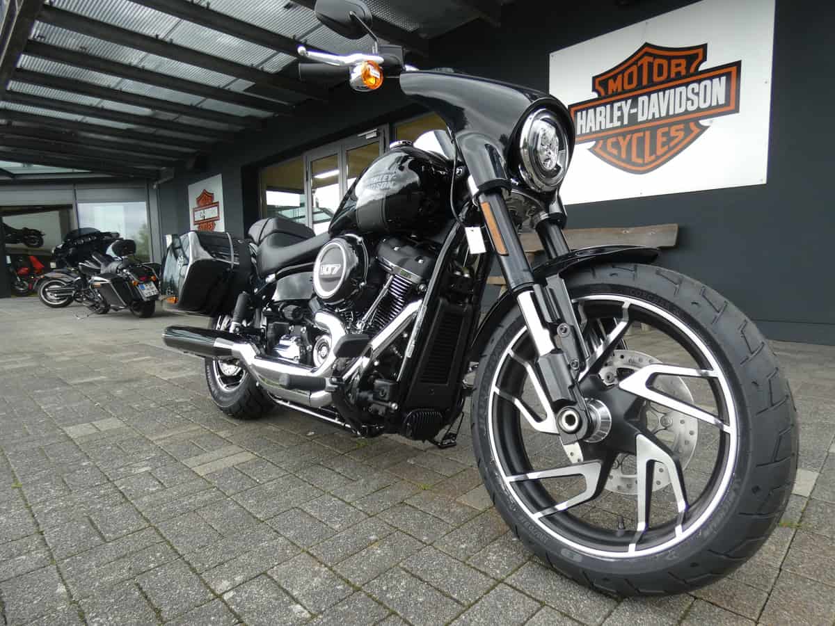 Harley-Davidson Motorrad vor dem Shop, schwarze Ausführung, große Reifen, modernes Design.