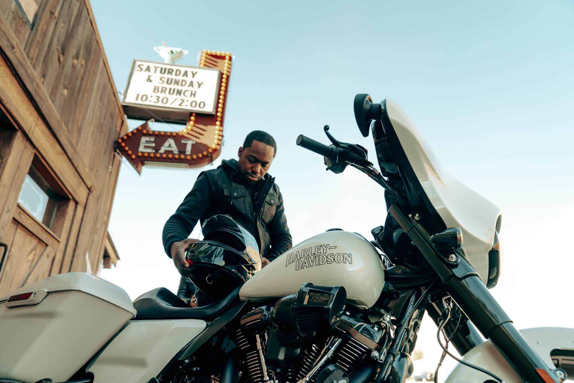 Leichtes Harley-Davidson Motorrad mit Fahrer und Helm vor EAT-Menütafel.