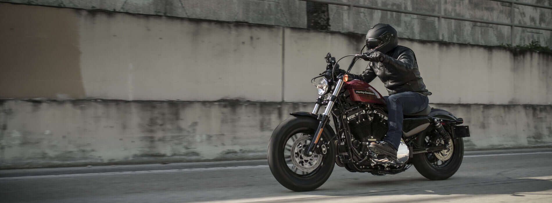 Harley-Davidson Motorradfahrer in Lederjacke und Helm auf Straße unterwegs.